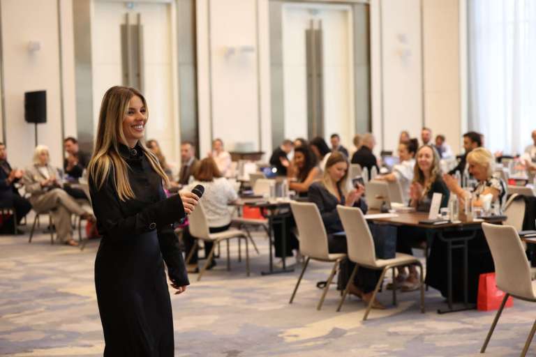 A smiling speaker with a microphone interacting with the audience during the conference